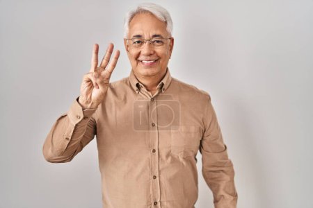 Téléchargez les photos : Hispanic senior man wearing glasses showing and pointing up with fingers number three while smiling confident and happy. - en image libre de droit