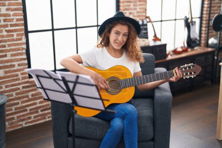 Foto de Joven hermosa mujer hispana músico tocando la guitarra clásica en el estudio de música - Imagen libre de derechos
