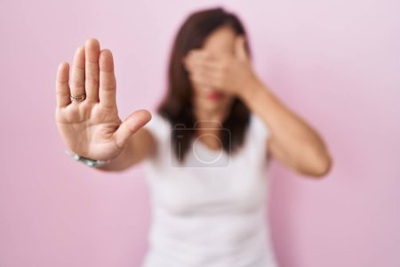 Photo for Middle age brunette woman standing over pink background covering eyes with hands and doing stop gesture with sad and fear expression. embarrassed and negative concept. - Royalty Free Image