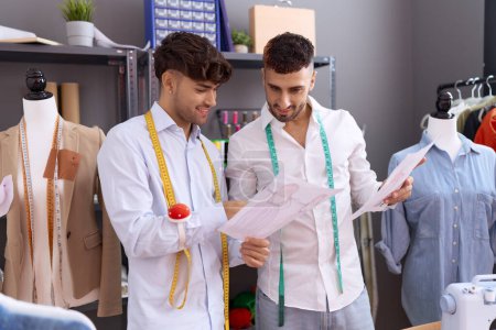 Téléchargez les photos : Two hispanic men tailors looking clothing design speaking at atelier - en image libre de droit