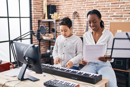 Téléchargez les photos : African american mother and son student learning play piano at music studio - en image libre de droit