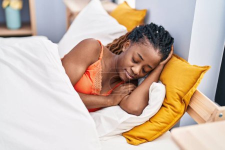 Femme afro-américaine couchée sur le lit dormant dans la chambre