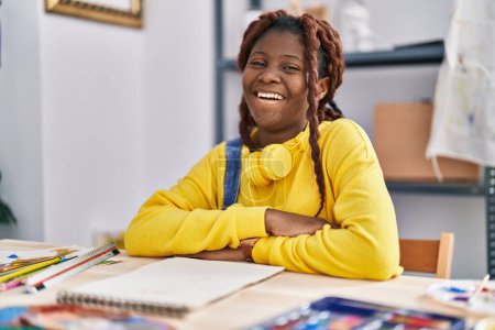 Photo for African american woman artist smiling confident sitting on table at art studio - Royalty Free Image