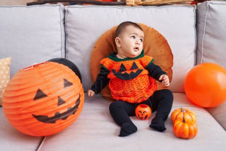 Photo for Adorable hispanic baby having halloween party sitting on sofa at home - Royalty Free Image