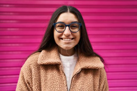 Téléchargez les photos : Jeune femme hispanique souriant confiant debout dans la rue - en image libre de droit