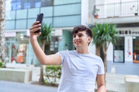 Foto de Hombre no binario sonriendo confiado haciendo selfie por el teléfono inteligente en la calle - Imagen libre de derechos