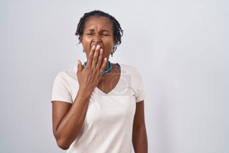 Téléchargez les photos : African woman with dreadlocks standing over white background bored yawning tired covering mouth with hand. restless and sleepiness. - en image libre de droit