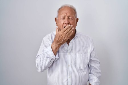 Foto de Senior man with grey hair standing over isolated background bored yawning tired covering mouth with hand. restless and sleepiness. - Imagen libre de derechos