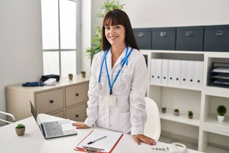 Photo for Young beautiful hispanic woman doctor smiling confident standing at clinic - Royalty Free Image