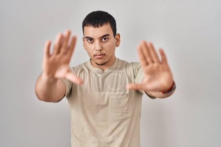 Photo for Young arab man wearing casual t shirt doing frame using hands palms and fingers, camera perspective - Royalty Free Image
