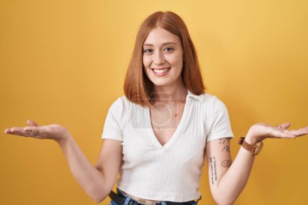 Téléchargez les photos : Jeune rousse femme debout sur fond jaune souriant joyeuse offrant les mains donnant de l'aide et l'acceptation. - en image libre de droit
