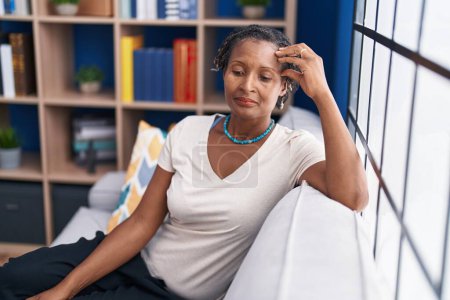 Foto de Mujer afroamericana de mediana edad estresada sentada en el sofá en casa - Imagen libre de derechos