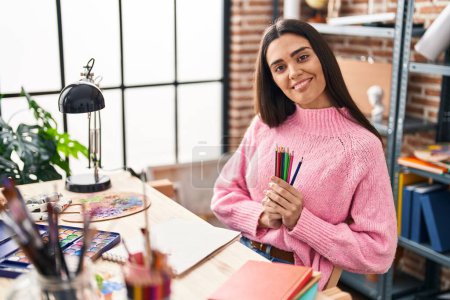 Photo for Young hispanic woman smiling confident holding pencils at art studio - Royalty Free Image