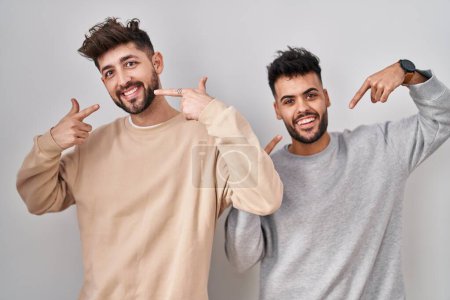 Téléchargez les photos : Young homosexual couple standing over white background smiling cheerful showing and pointing with fingers teeth and mouth. dental health concept. - en image libre de droit