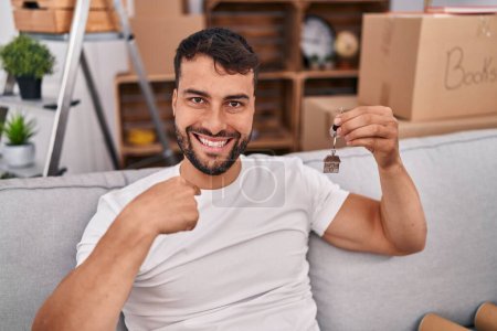 Photo for Handsome hispanic man holding keys of new home pointing finger to one self smiling happy and proud - Royalty Free Image
