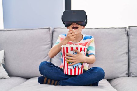 Téléchargez les photos : Blond child watching movie by virtual reality glasses at home - en image libre de droit