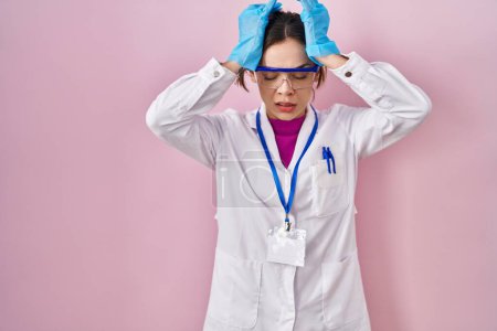 Téléchargez les photos : Femme hispanique portant uniforme scientifique souffrant de maux de tête désespérés et stressés parce que la douleur et la migraine. mains sur la tête. - en image libre de droit