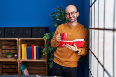 Photo for Young man reading book and drinking coffee at home - Royalty Free Image