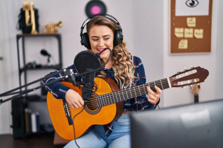 Foto de Young woman musician singing song playing classical guitar at music studio - Imagen libre de derechos