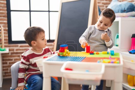 Photo for Two kids playing with construction blocks sitting on table at kindergarten - Royalty Free Image