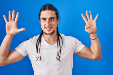 Photo for Hispanic man with long hair standing over blue background showing and pointing up with fingers number nine while smiling confident and happy. - Royalty Free Image