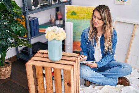 Téléchargez les photos : Jeune femme artiste dessin fleur sur ordinateur portable assis sur le sol à l'atelier d'art - en image libre de droit