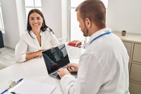 Photo for Young hispanic woman at the doctor looking positive and happy standing and smiling with a confident smile showing teeth - Royalty Free Image
