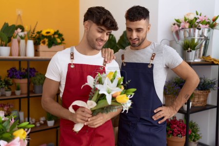 Foto de Two hispanic men florists smiling confident holding bouquet of flowers at flower shop - Imagen libre de derechos