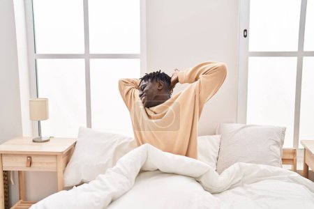 Foto de Hombre afroamericano despertando estirando brazos en el dormitorio - Imagen libre de derechos