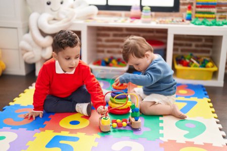 Foto de Dos niños jugando con aros de juguete sentado en el suelo en el jardín de infantes - Imagen libre de derechos