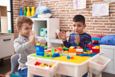 Foto de Two kids playing with construction blocks sitting on table at kindergarten - Imagen libre de derechos