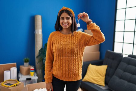 Photo for Young latin woman smiling confident holding key of new house at new home - Royalty Free Image