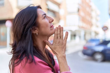 Photo for Middle age hispanic woman praying with closed eyes at street - Royalty Free Image