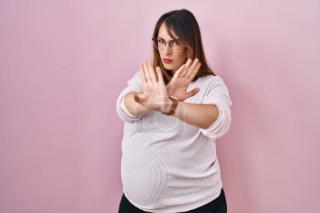 Téléchargez les photos : Femme enceinte debout sur fond rose expression de rejet croisant les bras faisant signe négatif, visage en colère - en image libre de droit