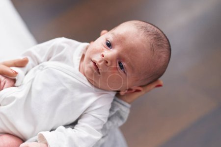 Foto de Adorable caucasian baby on mother arms at home - Imagen libre de derechos