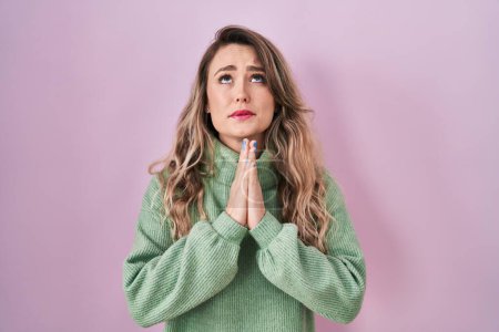 Téléchargez les photos : Young caucasian woman standing over pink background begging and praying with hands together with hope expression on face very emotional and worried. begging. - en image libre de droit