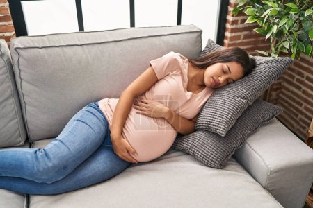 Photo for Young latin woman pregnant sleeping on sofa at home - Royalty Free Image