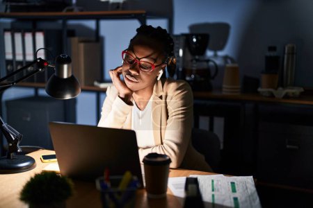 Téléchargez les photos : Beautiful black woman working at the office at night thinking looking tired and bored with depression problems with crossed arms. - en image libre de droit