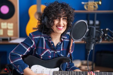 Photo for Young middle east woman artist singing song playing electrical guitar at music studio - Royalty Free Image