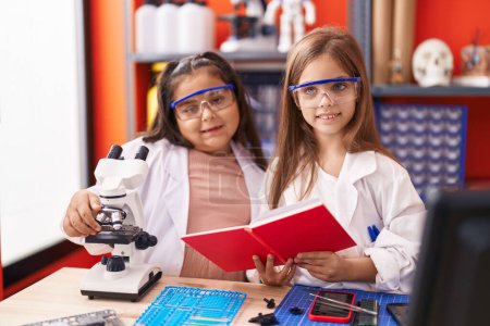 Téléchargez les photos : Deux élèves utilisent un cahier de lecture au microscope dans une salle de classe de laboratoire - en image libre de droit