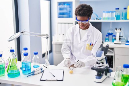 Foto de Mujer afroamericana vistiendo uniforme científico analizando muestra en laboratorio - Imagen libre de derechos