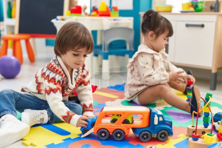 Foto de Dos niños jugando con coches juguete sentado en el suelo en el jardín de infantes - Imagen libre de derechos