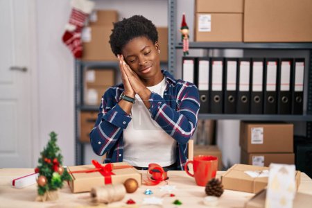 Téléchargez les photos : African american woman working at small business doing christmas decoration sleeping tired dreaming and posing with hands together while smiling with closed eyes. - en image libre de droit