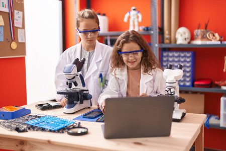 Photo for Two kids students using microscope and laptop at laboratory classroom - Royalty Free Image