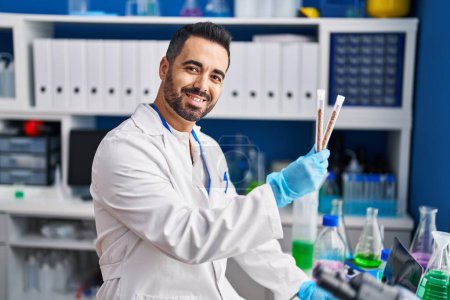 Photo for Young hispanic man scientist smiling confident holding test tubes at laboratory - Royalty Free Image