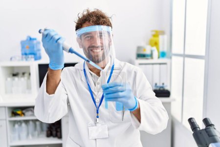 Photo for Young hispanic man wearing scientist uniform working at laboratory - Royalty Free Image