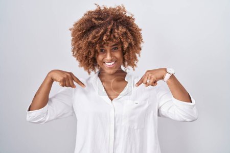 Photo for Young hispanic woman with curly hair standing over white background looking confident with smile on face, pointing oneself with fingers proud and happy. - Royalty Free Image