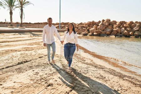 Téléchargez les photos : Homme et femme couple souriant heureux marche au bord de la mer - en image libre de droit