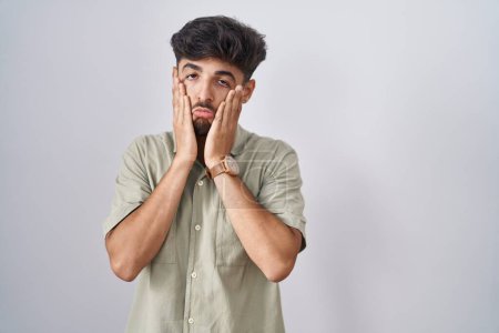 Photo for Arab man with beard standing over white background tired hands covering face, depression and sadness, upset and irritated for problem - Royalty Free Image
