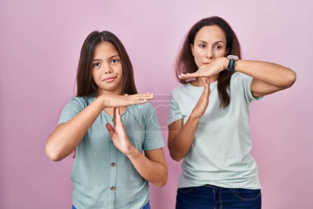 Photo for Young mother and daughter standing over pink background doing time out gesture with hands, frustrated and serious face - Royalty Free Image